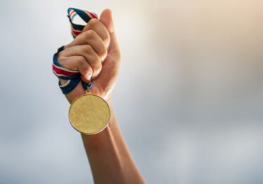 Hand holding medal, sympolising Paris Olympics is coming